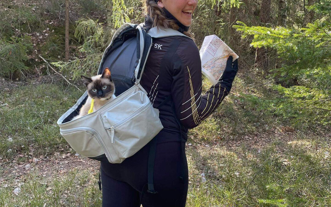 Lisa i skogen med en katt i en ryggsäck