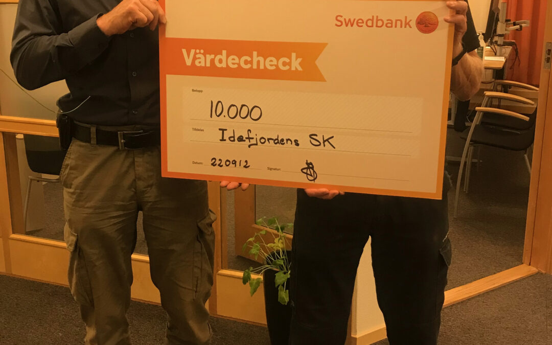 Rune Sandin och Bengt Bivrin håller upp en check på 10000 kr mellan sig inne på banken.